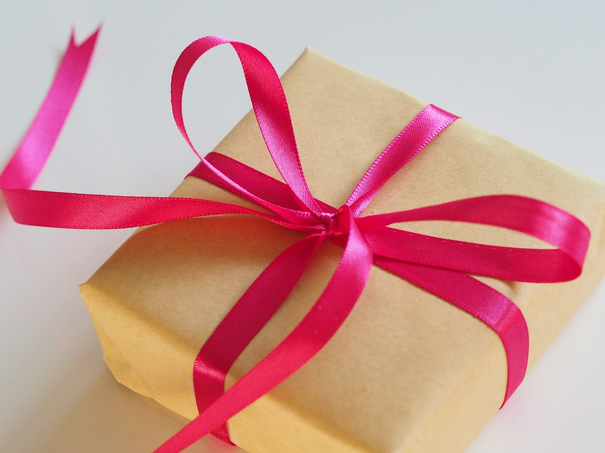 Cadeau emballé en papier kraft avec un ruban rose, idée cadeau padel