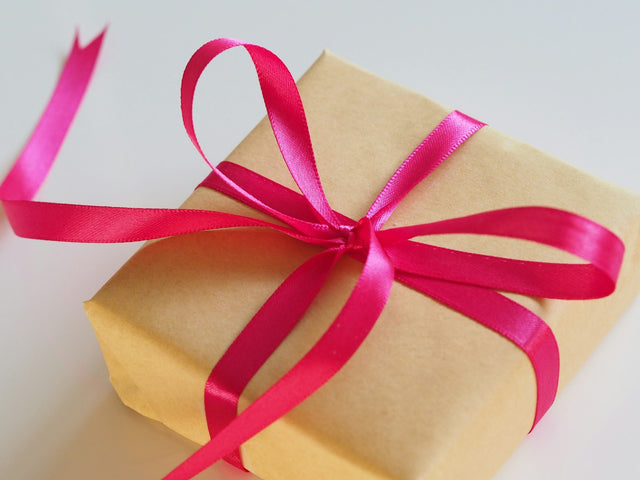 Cadeau emballé en papier kraft avec un ruban rose, idée cadeau padel