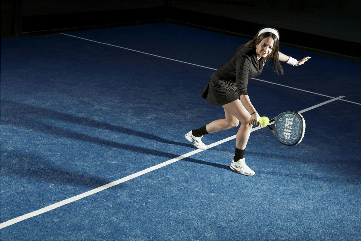 Joueuse de padel frappant la balle sur un court bleu