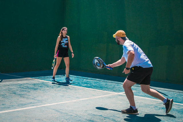 Deux joueurs de padel débutants échangeant sur le court